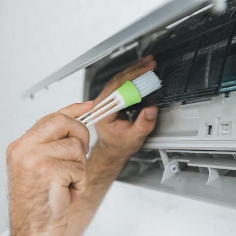 HVAC Contractor Cleans an AC.